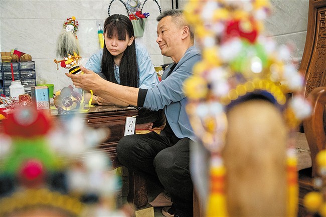 指导女儿许佳钿制作木偶盔头。